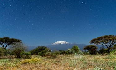 A breathtaking view of Mount Kilimanjaro framed by a clear starry night sky from Kajiado County, Kenya.